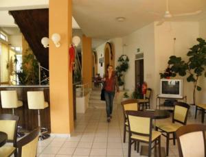 a woman walking through a restaurant with tables and chairs at Falassarna Hotel in Chania