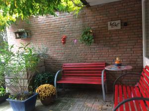 una panchina rossa seduta di fronte a un muro di mattoni di Bed and Breakfast De Mozaiektegel Uden a Uden