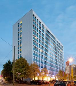een hoog wit gebouw met auto's geparkeerd voor het bij Boardinghouse Düsseldorf in Düsseldorf