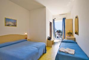 a hotel room with two beds and a balcony at Hotel Riva del Sole in Ischia