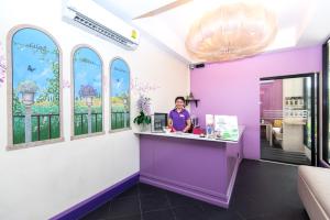 a woman standing at a counter in a room with windows at Lilac Relax-Residence in Lat Krabang