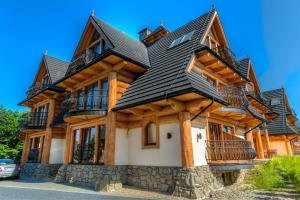 une grande maison en bois avec un toit noir dans l'établissement APARTAMENT PAJO I -Rezydencja Tatry, à Zakopane