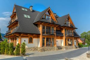 une grande maison en bois avec un toit noir dans l'établissement Apartament PAJO I -Rezydencja Tatry--GROTA SOLNA--TARAS--GARAŻ PODZIEMNY, à Zakopane
