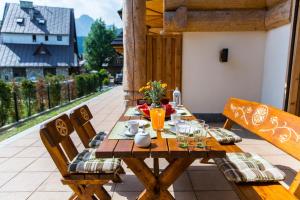 une table et des chaises en bois sur une terrasse dans l'établissement Apartament PAJO I -Rezydencja Tatry--GROTA SOLNA--TARAS--GARAŻ PODZIEMNY, à Zakopane