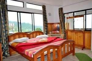 a bedroom with a wooden bed and a large window at Highcliffe Guest House in Haputale