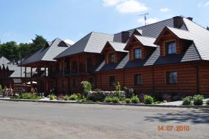 uma grande casa de madeira com um telhado preto em Oberza Knieja em Raducki Folwark