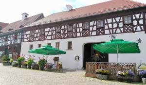 a building with two green umbrellas in front of it at Zum Egerländer Fachwerkhof in Neualbenreuth