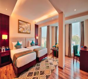 Golden Tulip Essential Jaipur في جايبور: غرفة فندقية بسريرين ونافذة