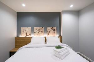 1 dormitorio con 1 cama blanca y 3 cuadros en la pared en VILLA23 Residence en Bangkok