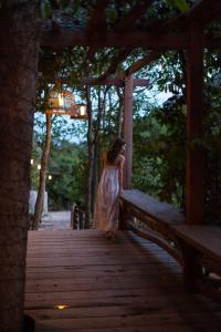 
a woman standing on a wooden bench in front of a forest at Veranda Natural Resort in Kep
