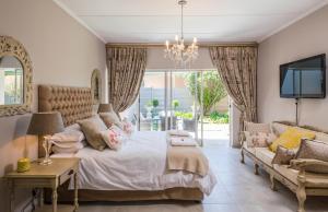 a bedroom with a bed and a couch and a tv at La Vida Luka - Luxury Guesthouse in Pretoria