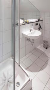 a white bathroom with a sink and a shower at Hotel Blechhammer in Kaiserslautern