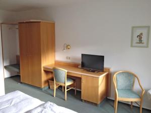 a bedroom with a desk with a television and two chairs at Gasthof Pension Walther in Weißdorf