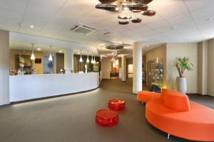 un vestíbulo de oficina con un sofá naranja y un mostrador en B&B HOTEL Montbéliard-Sochaux en Sochaux