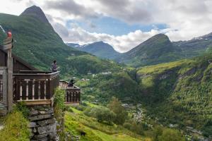 a man sitting on a balcony overlooking a valley at Westerås Gard in Geiranger