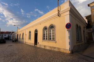 a yellow building with windows on a street at Ericeira Soul Guesthouse in Ericeira