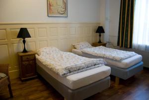 two twin beds in a room with a table at Pension Delfzijl in Delfzijl