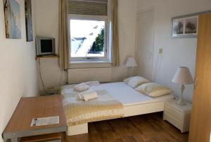 a small bedroom with a bed and a window at Pension Delfzijl in Delfzijl