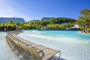 a row of chairs on a beach with blue water at Rio Quente Resorts - Hotel Pousada in Rio Quente