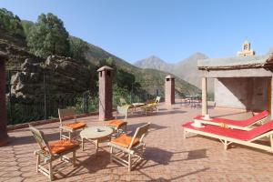 a patio with chairs and tables with mountains in the background at Hiba Lodge in Imlil
