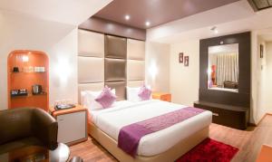 a bedroom with a bed and a chair and a mirror at Ritu Ivy in Kolkata