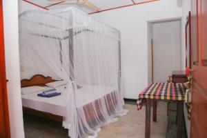 a bedroom with a canopy bed and a table at Tithira Guest House in Mirissa