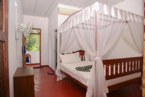 a bedroom with a bed with a canopy at Tithira Guest House in Mirissa
