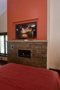 a bedroom with a fireplace with a tv on a wall at The Fields of Eden Inn in Eden