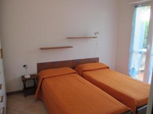 マリーナ・ディ・マッサにあるIl Castelluccio residenceのベッドルーム1室(オレンジのシーツが敷かれたベッド2台、窓付)