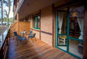 een patio met een tafel en stoelen op een houten terras bij Apartamenty Poddąbie in Poddąbie