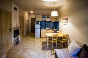 a kitchen and dining room with a table and a refrigerator at Apartamenty Poddąbie in Poddąbie