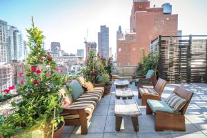 a rooftop patio with couches and tables and flowers at MADE Hotel in New York
