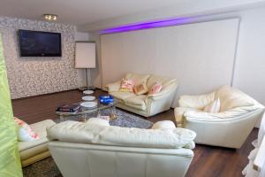 a living room with two white couches and a tv at Hotel Rosengarten in Schwäbisch Gmünd