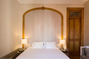 a bedroom with a large white bed with two lamps at Romantic - Casa Rua Bela in Porto