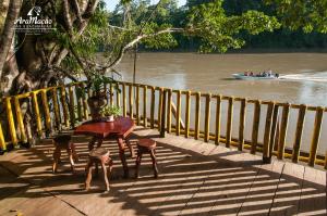 einen Tisch mit drei Hockern und einem Boot auf dem Fluss in der Unterkunft Las Guacamayas Lodge Resort, Selva Lacandona, Chiapas México in Tlatizapán