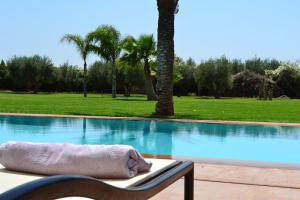 einen Sessel mit einem Kissen neben dem Pool in der Unterkunft Villa Jade in Marrakesch