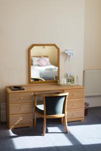 uma cómoda com um espelho e uma secretária com uma cadeira em Bayshore Hotel em Sandown