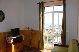 a living room with a television and a large window at Casa dos Caseiros in Santa Cruz
