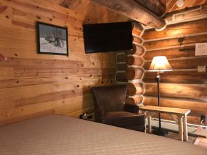 Un dormitorio con una cama y una silla y un televisor. en Judith Mountain Lodge, en Lewistown