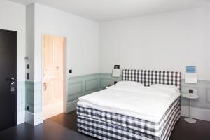 a bedroom with a white bed with a checked blanket at Boutique Hotel Helvetia in Zurich