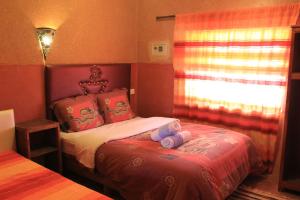 a bedroom with a bed with two stuffed animals on it at Maison d'Hôtes Nouflla in Aït Benhaddou