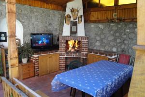 Habitación con chimenea, mesa y TV. en Guest House Zlatev, en Bansko