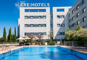 a hotel with a swimming pool in front of a building at Exe Madrid Norte in Madrid