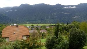 a small house in a field with mountains in the background at Monolocale Belvedere in Bovec