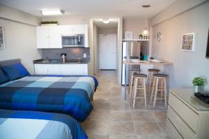 a bedroom with a bed and a kitchen with stools at Daytona Beach Club Studios! in Daytona Beach