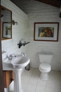 a white bathroom with a toilet and a sink at Bosque Protector Hacienda Guamag in Ba&ntilde;os
