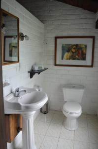 a white bathroom with a toilet and a sink at Bosque Protector Hacienda Guamag in Baños