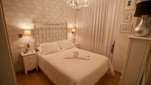 Un dormitorio con una cama blanca con un osito de peluche. en Apartamento Spellos, en Rosal