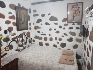 a bedroom with a bed and a rock wall at Casa Canaria Tejeda in Tejeda