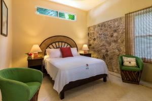 a bedroom with a bed and a green chair at Hotel Villas El Encanto Cozumel in Cozumel